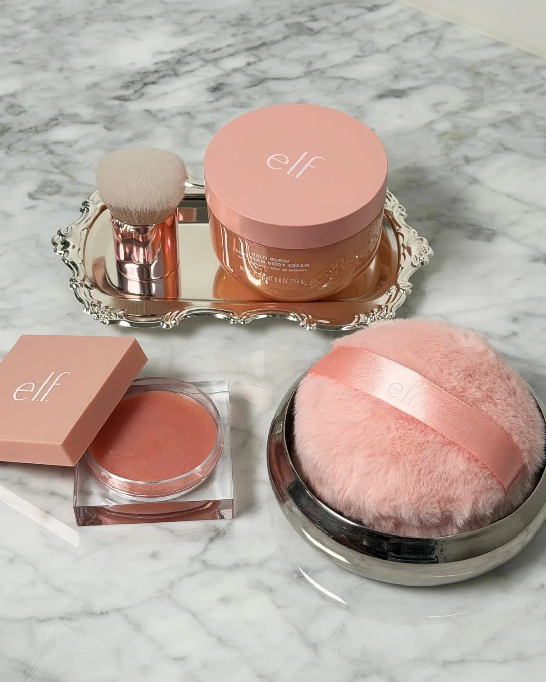 e.l.f. Cosmetics — Halo Glow body products arranged on a marble surface