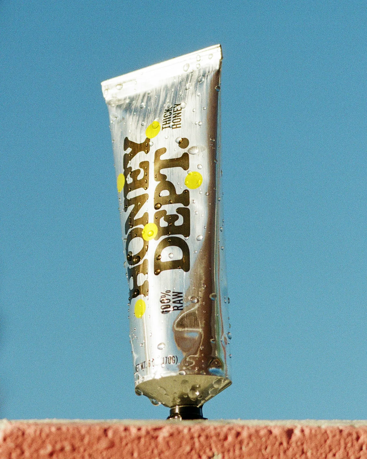 Honey Department — Metallic honey tubes by the pool and on a striped towel