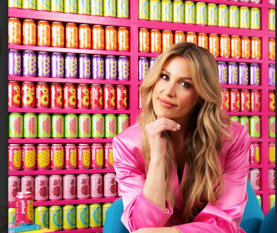 Poppi co-founder Allison Ellsworth, resting her chin on her hand, in front of colorful soda cans